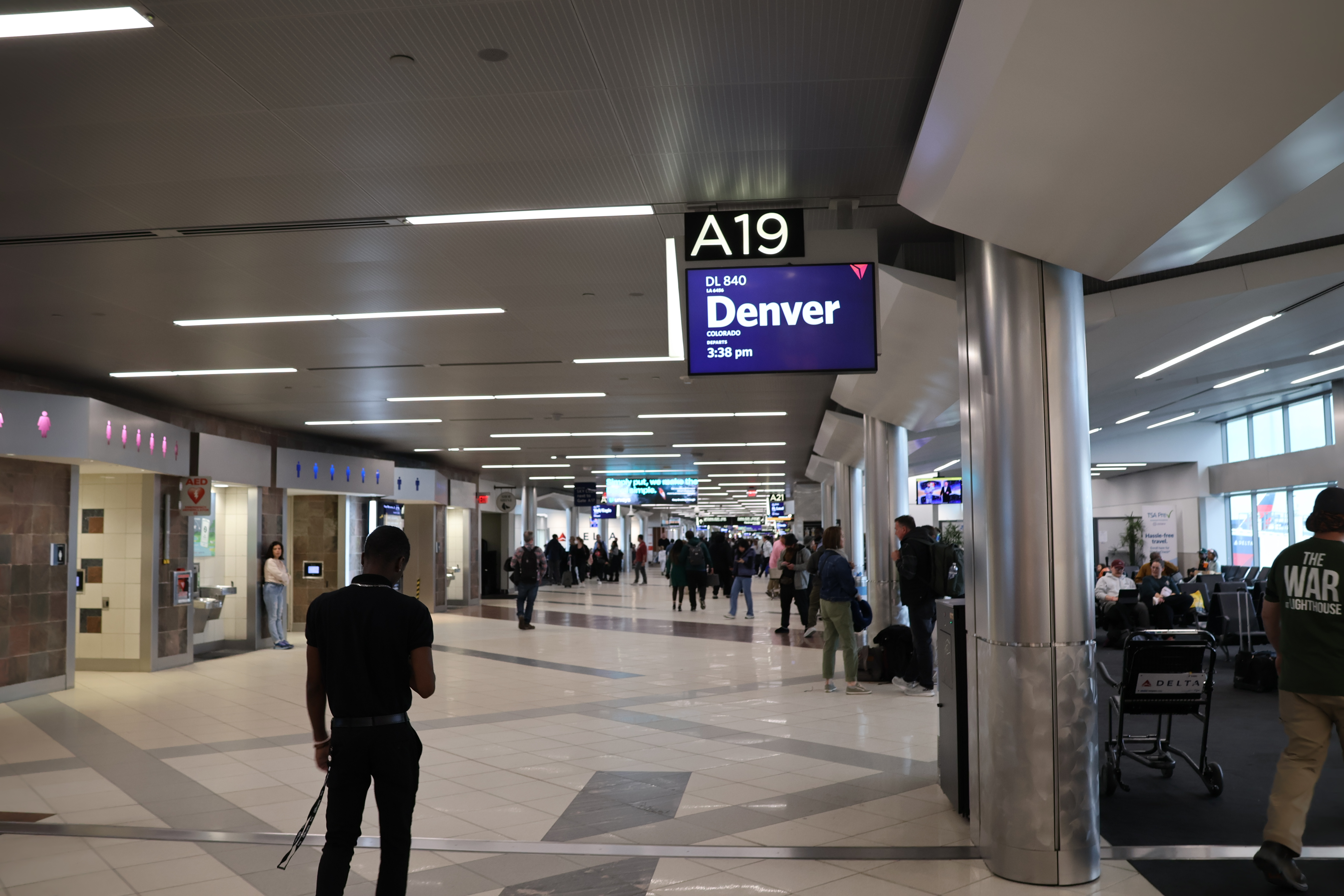 Interior photograph of Concourse A at gate A19 in December 2023, looking along the concourse corridor with gate hold-room seating, overhead signage and shopfronts