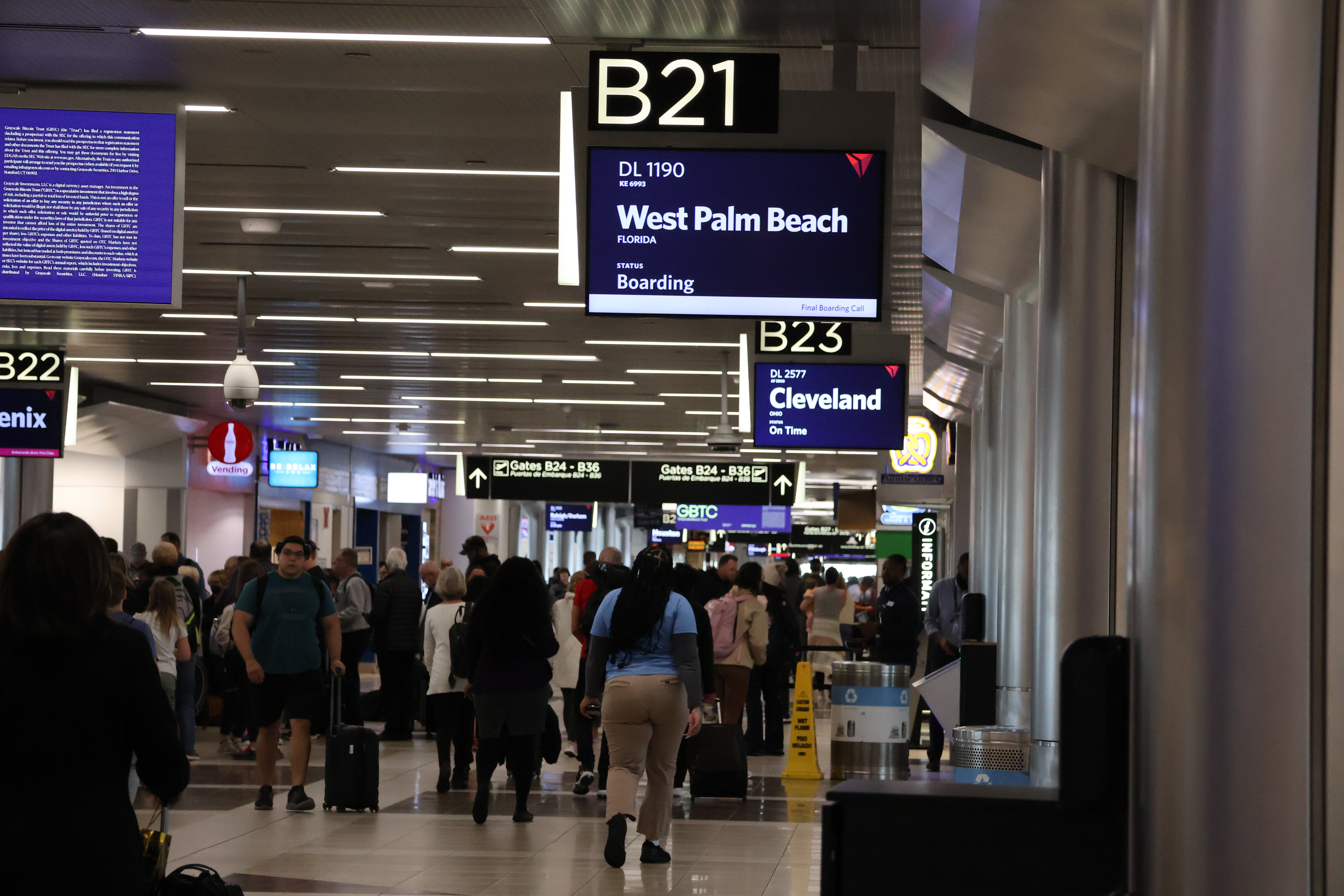 Interior photograph of Concourse B in December 2023, with passengers queuing to board at gate B21 beside the gate podium and hold-room seating