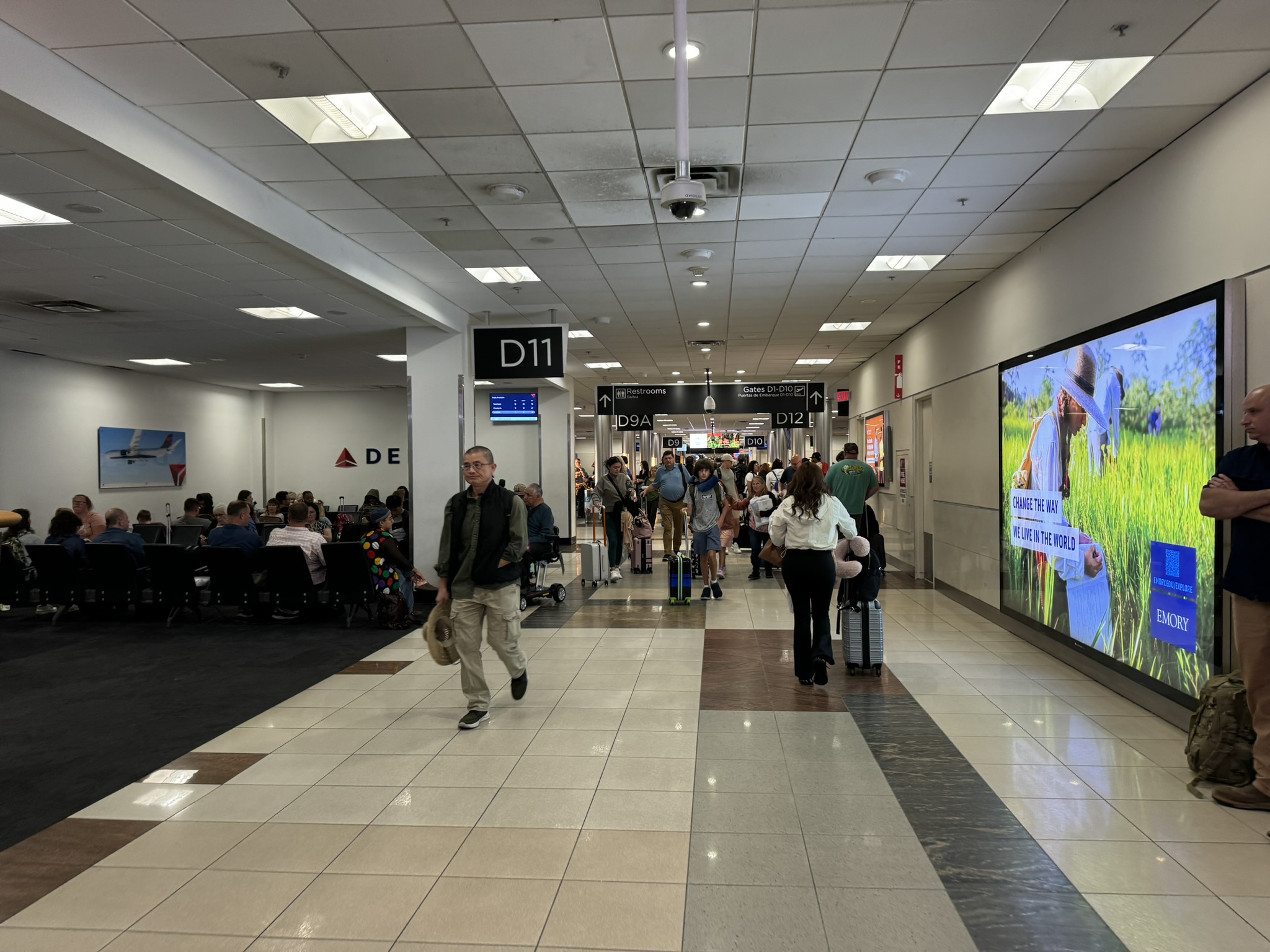 Interior photograph of the Concourse D gate D11 hold room in August 2024 during the widening program, with rows of seating, the gate podium and windows onto the apron