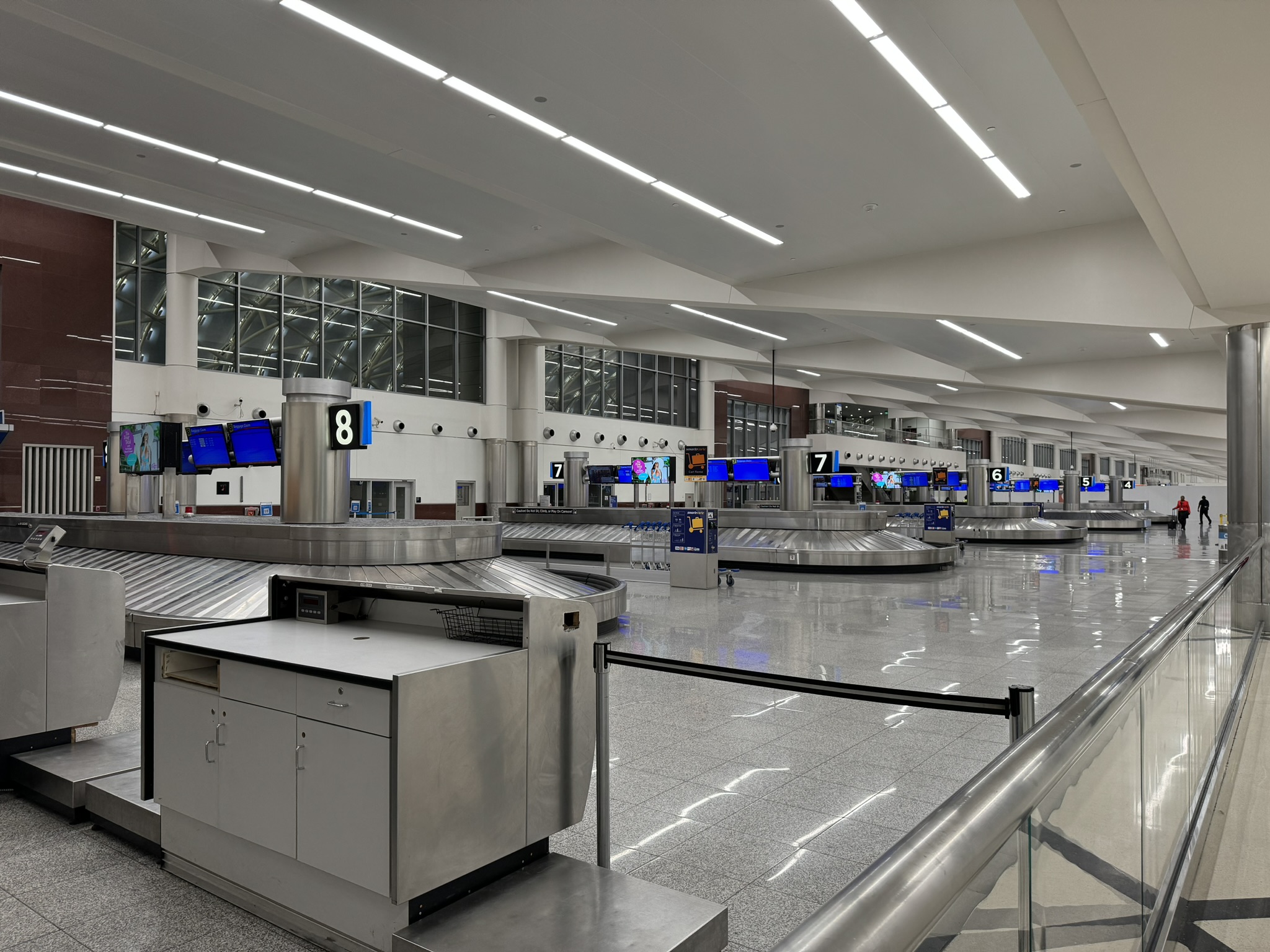 Photograph of the Domestic Terminal baggage claim hall in August 2024, with baggage carousel 8 and its overhead flight display