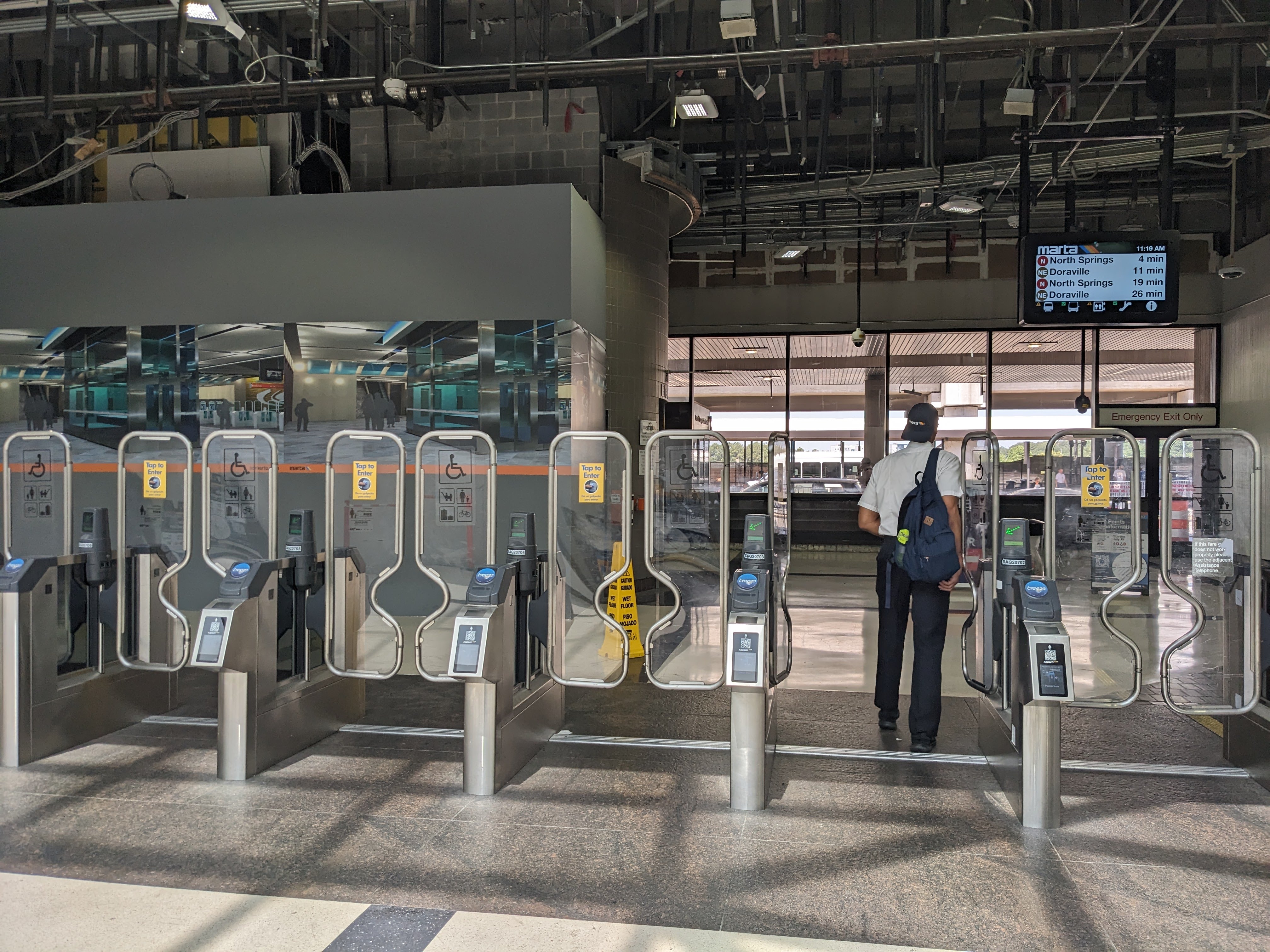Photograph of the MARTA Airport Station fare gates at the west end of the Domestic Terminal in June 2024, with a row of fare gates and the station concourse beyond