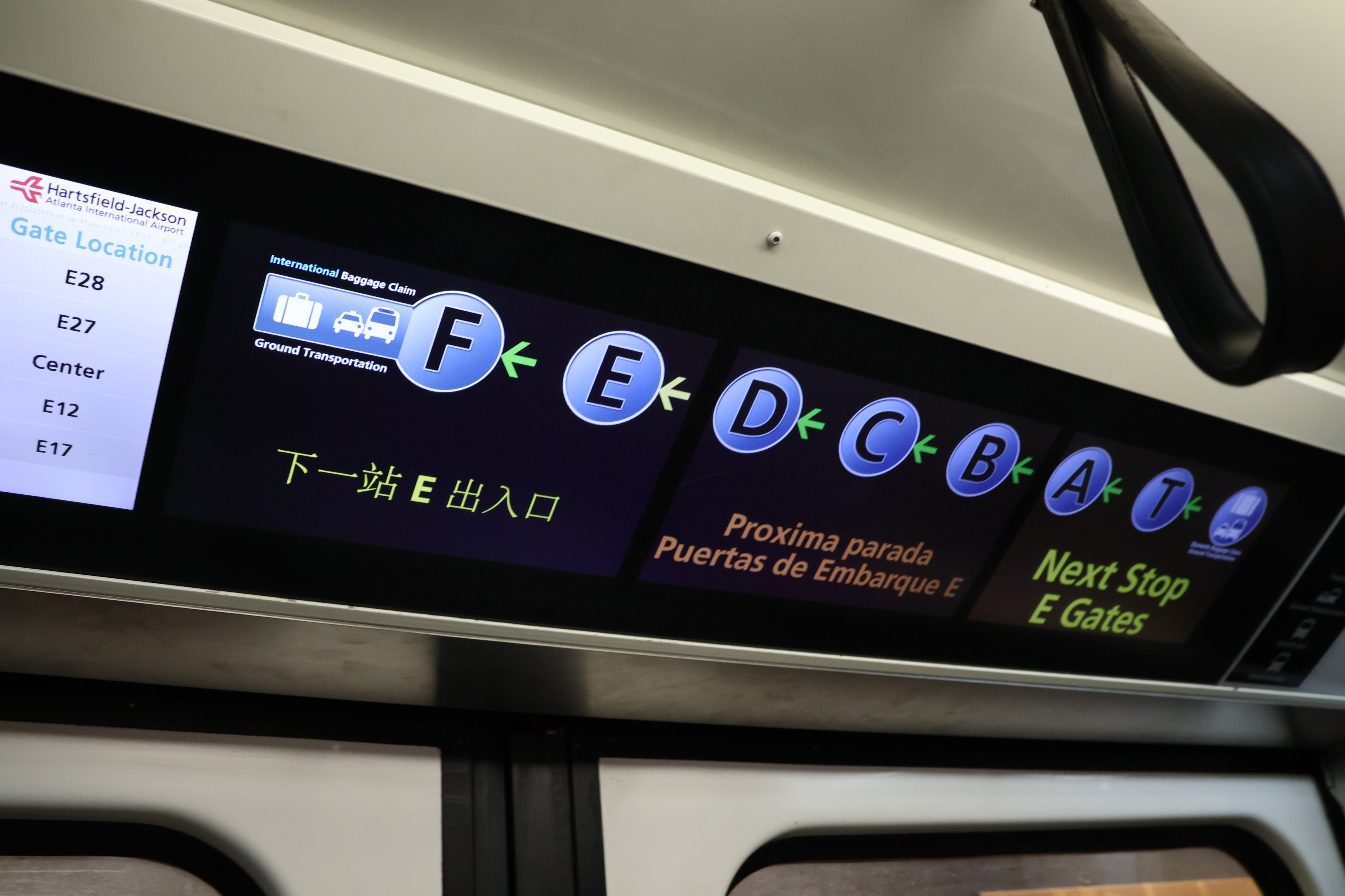 Photograph inside a Plane Train car in December 2023, with the in-car display listing the concourse sequence F, E, D, C, B, A, T